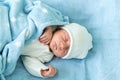 Newborn Baby Red Cute Face Portrait Early Days Sleeping In Medical Glass Bed On Blue Background. Child At Start Minutes Royalty Free Stock Photo