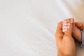 Newborn baby securely grasping his mother`s hands, close-up fingers