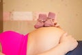 Newborn baby shoes on top of a pregnant woman's belly. Royalty Free Stock Photo