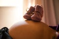 Newborn baby shoes on top of a pregnant woman's belly. Royalty Free Stock Photo