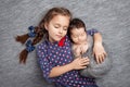 Newborn baby with sister. Cute girl lying with her little brother. Happy sister embracing her newborn baby brother