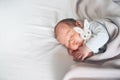 Newborn sleep at first days of life. Portrait of new born baby one week old with cute soft toy in crib in cloth background