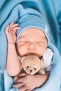 Newborn sleep at first days of life. Portrait of new born baby one week old with cute soft toy in crib in cloth background Royalty Free Stock Photo