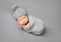 Newborn baby sleeping curled up in grey blanket