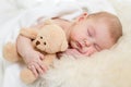 Baby with toy sleeping on fur bed