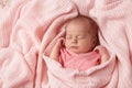 Newborn Baby sleeping in knitted Blanket. Cute Infant Child wrapped in Cotton Towel. New Born Little Girl resting in Pink Clothes Royalty Free Stock Photo