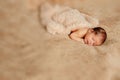 Newborn baby sleeping, resting on her own hands and elbows, on brown background Royalty Free Stock Photo