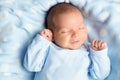 Newborn Baby Sleeping Smiling. Cute Infant Child in Wrap Bodysuit. New Born Little Boy smile in Blue Clothes lying on Blanket Royalty Free Stock Photo