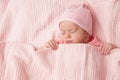 Newborn Baby sleeping under knitted Blanket. Cute Infant Child wrapped in Cotton Towel. New Born Little Girl resting in Pink Royalty Free Stock Photo