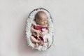 A newborn baby sleeps in a basket in a pink body with a small toy.