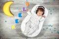 Newborn baby sleeps in a special orthopedic mattress Baby cocoon, on a wooden floor multicolored letters around. Calm Royalty Free Stock Photo