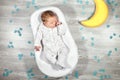 Newborn baby sleeps in a special orthopedic mattress Baby cocoon, on a wooden floor, toy moon and puzzles around. Calm Royalty Free Stock Photo