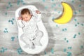 Newborn baby sleeps in a special orthopedic mattress Baby cocoon, on a wooden floor, toy moon and puzzles around. Calm Royalty Free Stock Photo