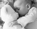 Newborn baby sleeps with a teddy bear black and white