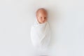 Newborn baby sleeps in white winding on a white background