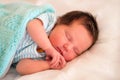 Newborn baby in striped shirt sleeping in bed under cyan woolen blanket. Calm infant child dreaming in bed