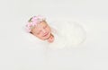 Newborn baby swaddled in white diaper smiling asleep