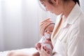 Newborn baby with teat was held by her Asian mother who is sitting on the bed and look to baby face with love Royalty Free Stock Photo