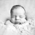 Newborn baby toddler boy or girl lies on hands on the fur and sleeps sweetly. Black and white picture Royalty Free Stock Photo