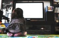 Newborn baby watch tv on the carpet in livingroom socks back view Royalty Free Stock Photo