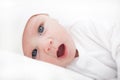 Newborn baby in white, yawns, looking at the camera Royalty Free Stock Photo