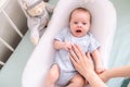 Newborn baby yawns, boy lying in nursery cocoon with blue clothes on bed in bedroom at home, happy baby morning. Royalty Free Stock Photo