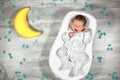 Newborn baby yawns in a special orthopedic mattress Baby cocoon, on a wooden floor, toy moon and puzzles around. Calm Royalty Free Stock Photo