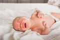 Newborn on the bed. Crying, screaming baby close up and copy space. Baby smile and colic in newborns. Seborrheic dermatitis in new