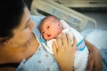 Newborn being held by Hispanic mother in hospital bed