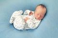 Newborn boy asleep on a blue background in white pajamas with a Royalty Free Stock Photo