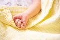 Newborn caucasian premature baby hand on pastel yellow soft muslin blanket soft focus. Copy space, space for text. Royalty Free Stock Photo