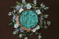 Newborn digital background - brown wooden bowl with green leaves wreath and  teal flowers Royalty Free Stock Photo