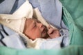 Newborn in the green blanket in the hospital, baby with eyes closed