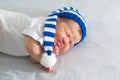 Newborn in hat on white blanket, asian baby stomach ache. Infant care, teething pain, colic ache