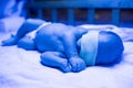 Newborn having a treatment for jaundice under ultraviolet lamp in home bed Royalty Free Stock Photo