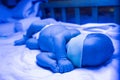 Newborn having a treatment for jaundice under ultraviolet lamp in home bed Royalty Free Stock Photo