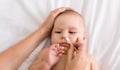 Mother cleaning baby nose with cotton swab