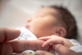 A newborn infant baby girl in a blanket swaddle wraps her tiny hand and fingers around her father and mother`s fingers as she Royalty Free Stock Photo