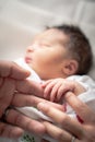 A newborn infant baby girl in a blanket swaddle wraps her tiny hand and fingers around her father and mother`s fingers as she Royalty Free Stock Photo
