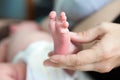 Newborn infant barefoot leg in female hand, mother breastfeeding baby lying in bed, close-up view Royalty Free Stock Photo