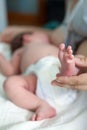 Newborn infant barefoot leg in women hand, mother breastfeeding baby lying in bed, close up view Royalty Free Stock Photo