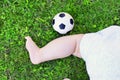 newborn kid laying on the grass with a small soccer ball