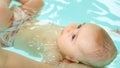 Newborn lays on back with help of swim teacher in water Royalty Free Stock Photo
