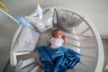 Newborn lies in the round white bed with mobile