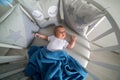 Newborn lies in the round white bed with mobile