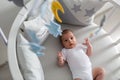 Newborn lies in the round white bed with mobile