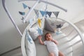 Newborn lies in the round white bed with mobile