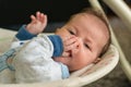 The newborn lies on swing automatic electrical chair and enjoys it
