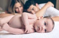 Newborn lying over bed and couple smiling on