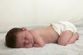 Newborn male caucasian baby sleeping on white blanket with diaper